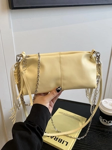 Minimalist light yellow pleated baguette bag with fringe detail and silver chain strap