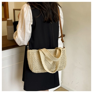 Detail of straw woven beach bag featuring brown leather strap and intricate grid pattern