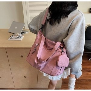 Detail view of pink nylon tote bag with pleated texture and side round zipper pouch