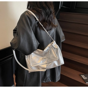 Detail of silver metallic shoulder bag with chain strap and crinkle texture on model