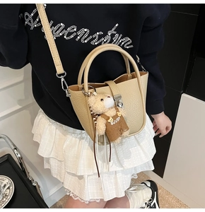 Detail of apricot lychee pattern bucket bag featuring a cute beige teddy bear charm