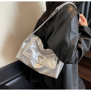 Detail of silver metallic pleated shoulder bag featuring a sleek rectangular metal plaque