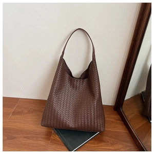 Close-up of premium dark brown woven leather texture on a spacious tote bag detail