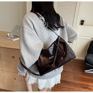Detail of dark brown chain shoulder bag in polished leather with silver metal hardware