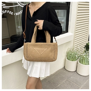 Detail of hollow-out straw handbag featuring iconic triangle weave and leather strap