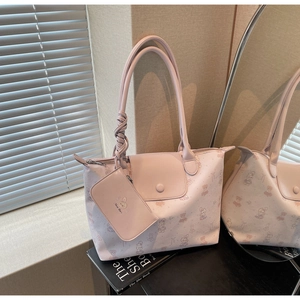 Pink tote bag with cartoon bear prints, knotted handles and mini pouch in soft natural light