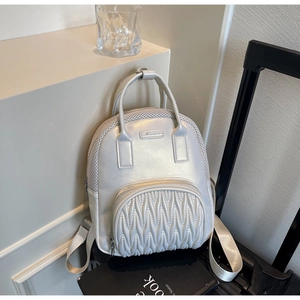 Close-up of quilted V-pattern texture and mesh detail on silver mini backpack