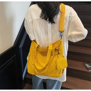 Détail d'un grand cabas en nylon jaune avec petit porte-monnaie et bandoulière réglable