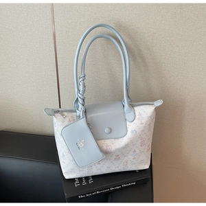 Detail of light blue tote bag set with cartoon print and small pouch on leather sofa