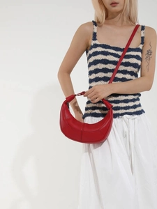Minimalist red crescent leather handbag shown as a crossbody shoulder bag on a model