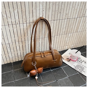 Détail d'un sac baguette rétro marron avec pendentif nœud et doubles anses en PU