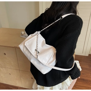 Detail of soft white leather shoulder bag featuring natural texture and silver chain strap