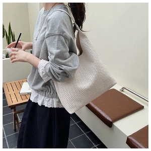 Close-up of beige woven tote bag texture and large hobo shoulder strap design