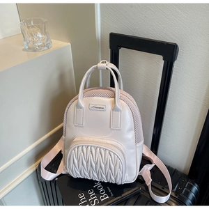 Close-up of pink pleated mini backpack with mesh texture on black suitcase