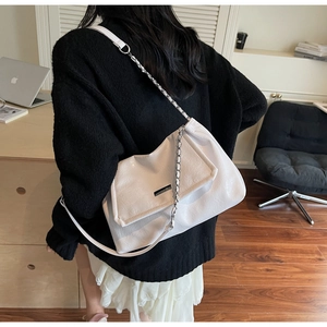 Detail of white leather shoulder bag featuring silver metal clasp and chain strap