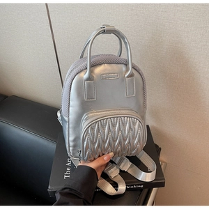 Close-up of metallic silver backpack featuring quilted texture and mesh side details