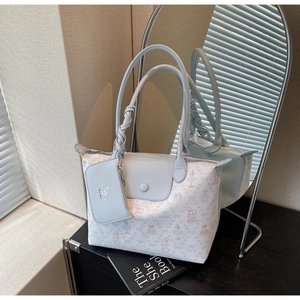Detail of light blue tote bag with pink rabbit prints and woven handle accents