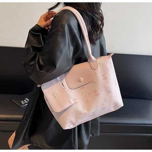Pink tote bag with cartoon pattern and matching coin purse on a model shoulder