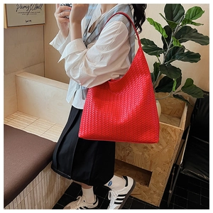 Detailed side view of a large red woven hobo bag worn by a model in a casual setting