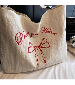 Detail of cream canvas tote bag with red Protect your Heart print and adjustable strap