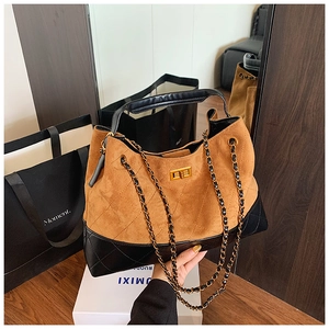 Détail du sac à bandoulière en daim matelassé avec chaîne dorée et fermoir pivotant