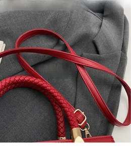 Detail of red bridal handbag featuring woven handles and long leather shoulder strap