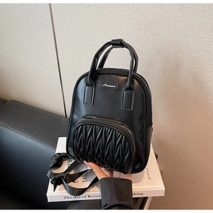 Detail of black PU leather mini backpack with wavy pleated pocket and metal logo plaque