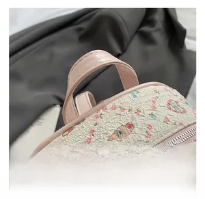 Detail of pink leather handles and silver zipper on white floral bubble textured backpack
