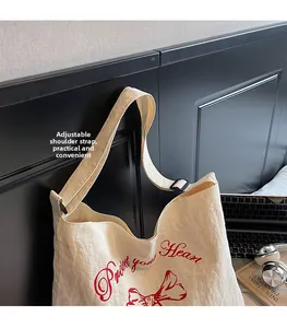 Detail of adjustable black buckle on a cream canvas tote bag with red printed text