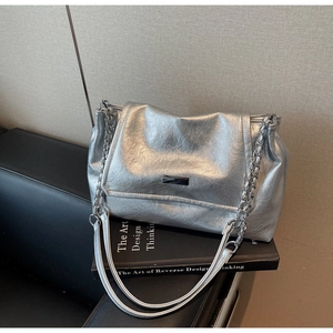 Detail of silver metallic wrinkled shoulder bag with chain strap on black books