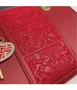Detail of red bridal handbag featuring floral embroidery and heart-shaped Xi charm