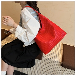 Macro shot of large bright red woven leather hobo shoulder bag with Intrecciato texture