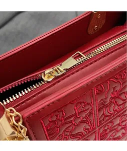 Close-up of golden zipper and floral embroidery detail on a red leather bridal handbag