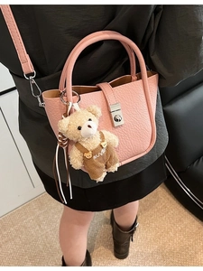 Pink faux leather bucket crossbody bag for women with a cute decorative teddy bear charm