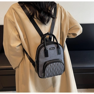Detail of grey fabric and black leather backpack with quilted front pocket design