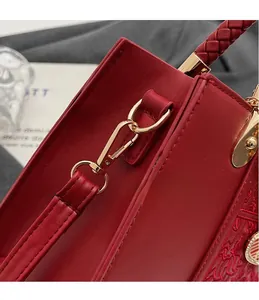 Close-up of golden metal hook on a red bridal handbag with floral embroidery details
