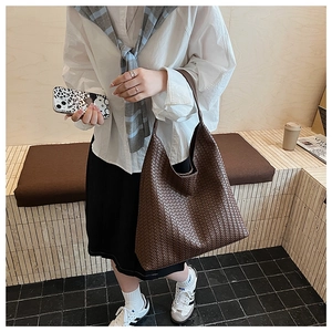 Close-up of deep brown leather woven tote bag showing detailed texture and large capacity