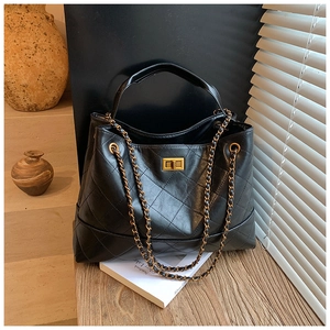 Détail du sac cabas en cuir matelassé noir avec fermoir doré et chaîne