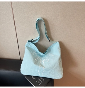 Detail of light blue canvas tote bag with bow print and adjustable black shoulder strap