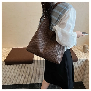 Detail of dark brown woven tote bag showing premium leather texture and spacious design