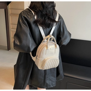 Detail view of white mini shoulder bag with mesh panels and pleated front pocket on model