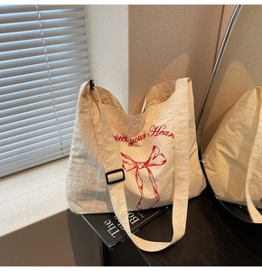 Detail of cream canvas tote bag with red bow print and Protect your Heart artistic lettering