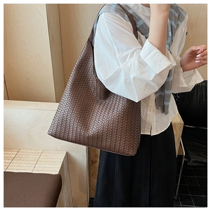 Close-up of a large coffee brown woven tote bag showing detailed leather craftsmanship