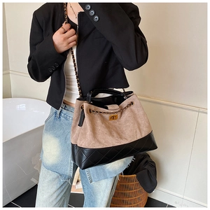 Détail d'un sac bandoulière bicolore en daim beige et cuir noir matelassé chic