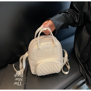 Close-up of beige mini backpack with mesh splicing and pleated front pocket detail