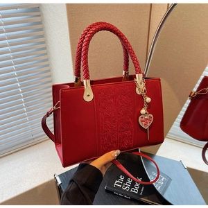 Detail of red bridal handbag with floral embossing, woven handle and pearl charm