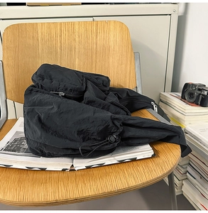 Detail of black nylon messenger bag with functional texture on a wooden chair