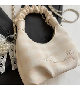 Detail of checkered dumpling bag with pearl lace pendant and heart embroidery on fabric