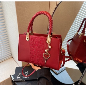 Detail of red bridal handbag with woven handle and heart-shaped wedding pendant