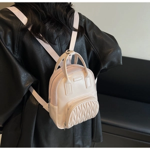 Detail of cream mini backpack featuring quilted pleated front pocket and top handle